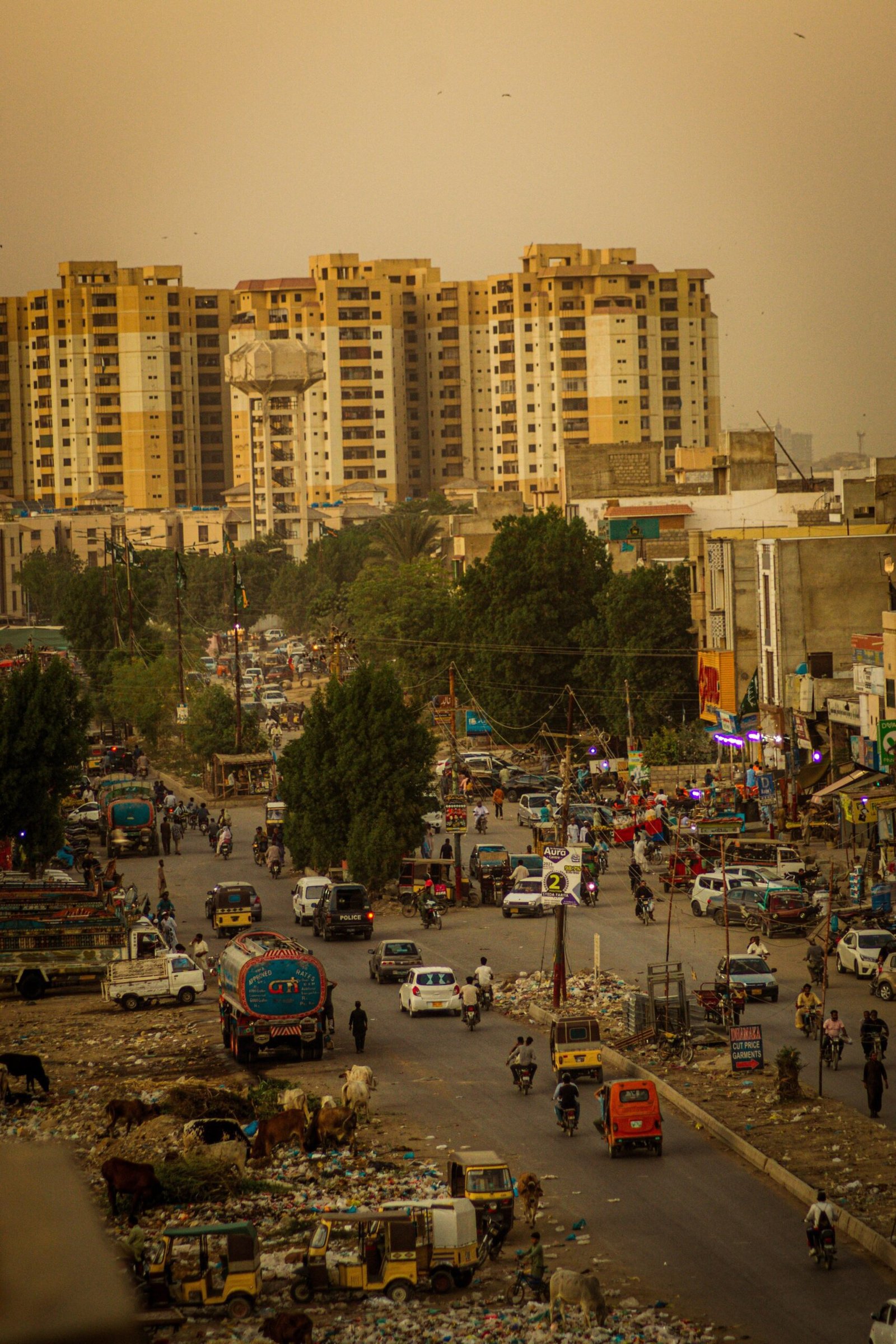 Busy Karachi street with high-rise commercial buildings and traffic at sunset