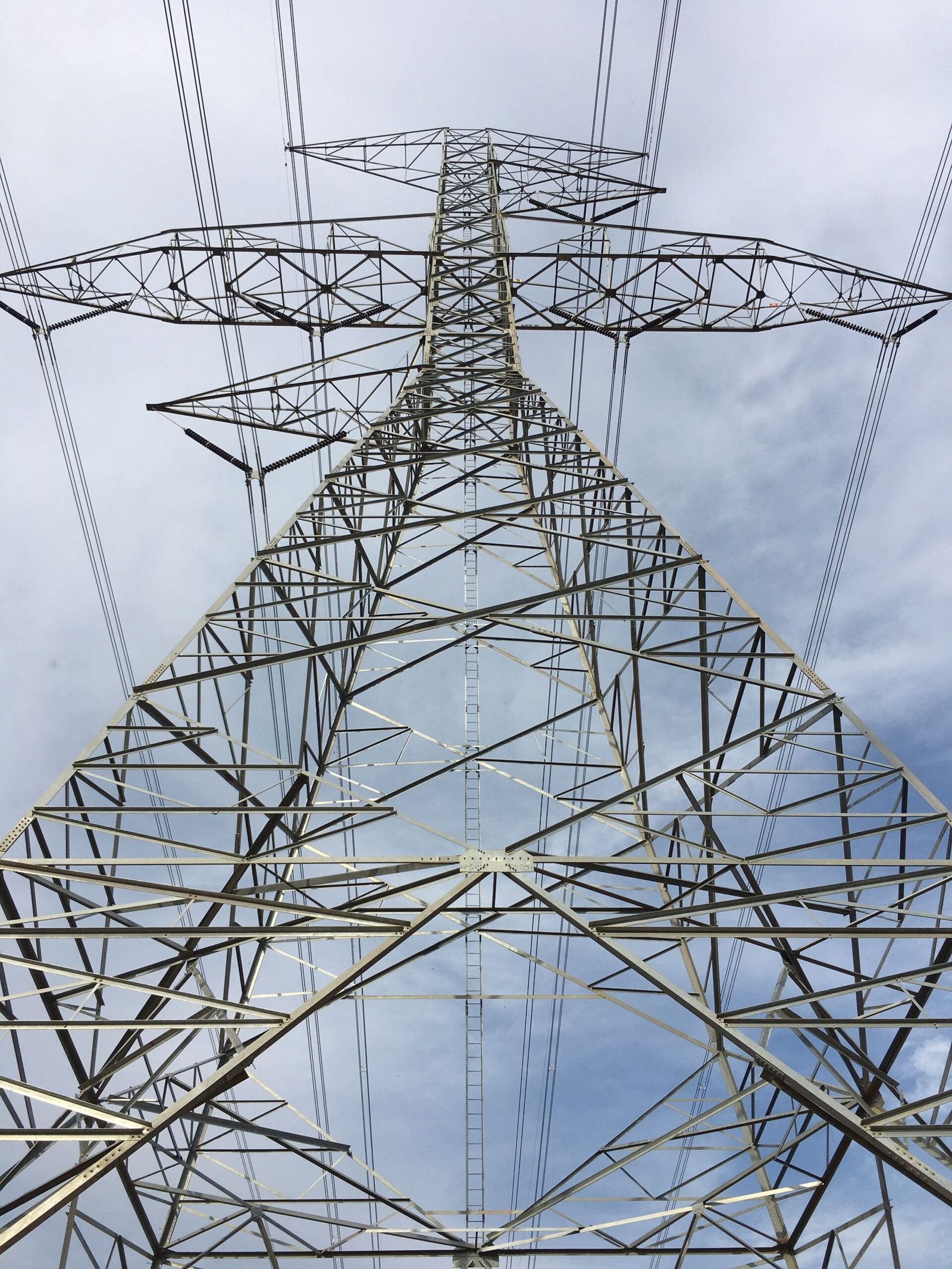 Steel electricity pylon against a blue sky carrying multiple power transmission lines