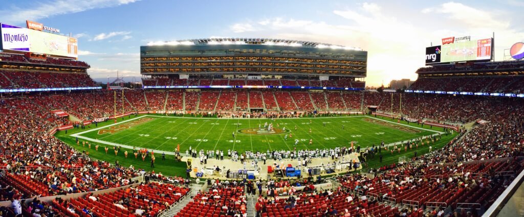 Why billionaires buy sports teams: packed NFL stadium showing live sports demand AI cannot replace