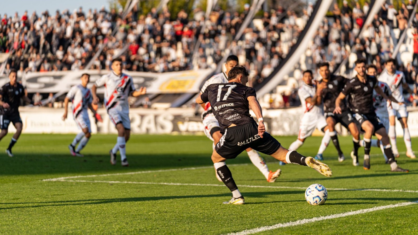 Players competing in a packed football stadium during a live match